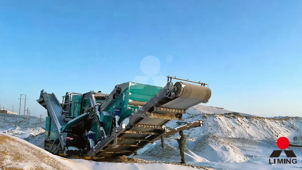 Maintenance technician inspecting the hydraulic tramming motors and frozen track pads of a crawler-mounted jaw crusher prior to initiating movement